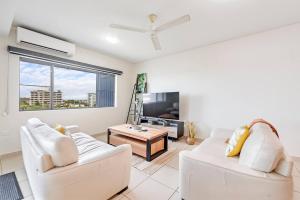 ein Wohnzimmer mit 2 weißen Sofas und einem TV in der Unterkunft Tropical Horizons - Chic Family Stay with Pool in Darwin