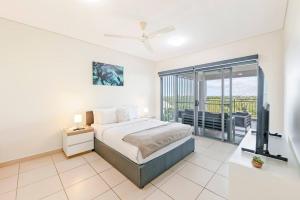 Schlafzimmer mit einem Bett, einem TV und einem Balkon in der Unterkunft Tropical Horizons - Chic Family Stay with Pool in Darwin + 26 Fotos