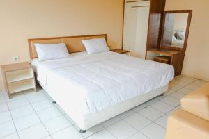 a bedroom with a large white bed and a mirror at Aurora Rooms Mutiara Bekasi in Pekayon Satu