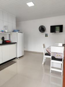 a kitchen with a refrigerator and a table and a chair at Apartamento kit aconchegante 1 in Matinhos