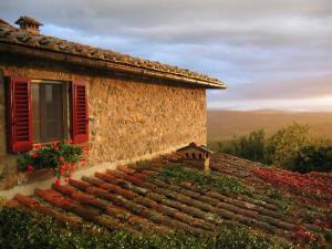 a stone building with red shutters and a window at Casa Ercole Farm Stay in Greve in Chianti