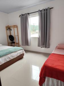 a bedroom with two beds and a window at Apartamento kit aconchegante 1 in Matinhos +13 photos