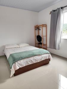 a white bedroom with a bed and a window at Apartamento kit aconchegante 1 in Matinhos