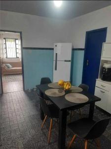 a kitchen with a black table with chairs and a table with bananas on it at Casa Praia Grande in Arraial do Cabo