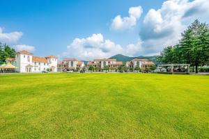 un grand champ vert avec des maisons en arrière-plan dans l'établissement Hongcheon Monterio Resort, à Hongcheon 7 autres photos