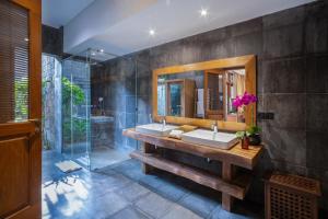 a bathroom with a sink and a mirror and a shower at Villa Kapungkur in Jimbaran