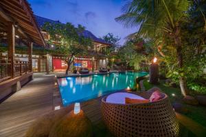 a resort swimming pool with a wicker chair next to it at Villa Kapungkur in Jimbaran