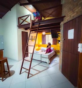 a woman sitting on a bed in a room with a ladder at Villa Justen Pousada in Lençóis