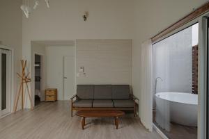 a bathroom with a bath tub and a couch and a bath tub at Jeju Sin-eom-an-gil A in Jeju