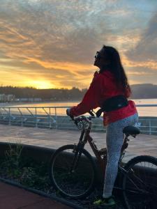 Una donna è in piedi accanto a una bicicletta di Hostal Duchantu a Dichato