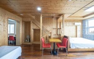 a bedroom with a bed and a desk and chairs at Jeju Joy Hill Pension in Jeju