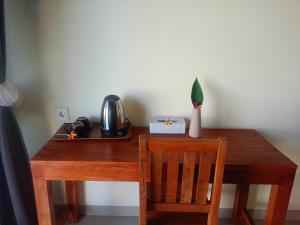 a wooden table with a chair and a tea kettle on it at HOME STAY ME'SARI tulamben in Tulamben