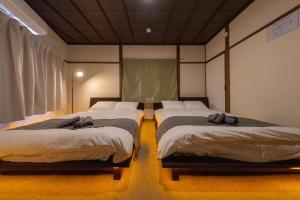 two beds sitting in a room at SORA usjまで電車で8分 5つの寝室 貸切の宿で楽しい時間を過ごしてください in Osaka