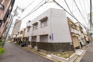 a white building on the side of a street at SORA usjまで電車で8分 5つの寝室 貸切の宿で楽しい時間を過ごしてください in Osaka