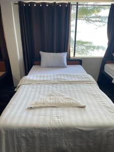 The ream beach hostel في Phsar Ream: سرير ابيض ومخدة عليه شباك