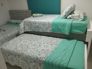 three beds in a room with green and white sheets at Green House in Cartagena de Indias