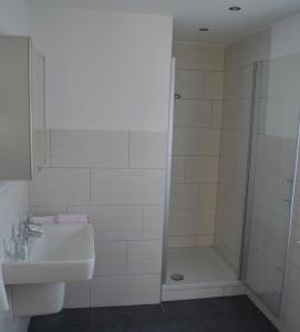 a white bathroom with a shower and a sink at Hotel Haus Rameil in Lennestadt
