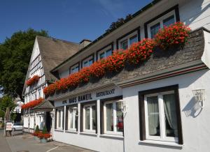 a building with red flowers on the side of it at Hotel Haus Rameil in Lennestadt