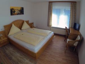 a bedroom with a bed and a desk and a window at Hotel Haus Rameil in Lennestadt