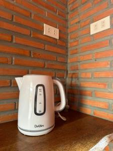 a tea kettle sitting on a table next to a brick wall at Thusan House - Mekong Homestay in Ấp Vĩnh An (1)