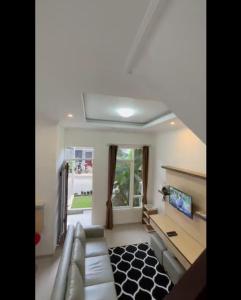 a living room with a couch and a tv at Villa Indragiri in Songgoriti