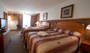 a hotel room with two beds and a flat screen tv at Motel Du Chevalier in Gatineau