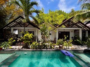 a villa with a swimming pool in front of a house at Alibaba Bungalows in Gili Islands