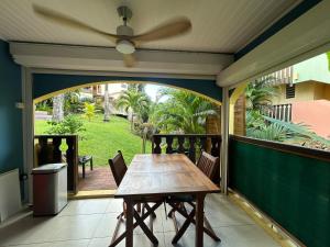 a table on a screened porch with a ceiling fan at Studio palmiers royaux in Sainte-Anne