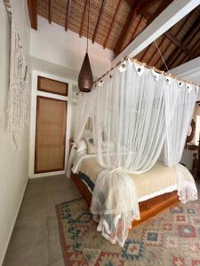 a bedroom with a bed with white mosquito nets at Santai Villas in Nusa Lembongan +30 photos