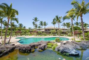 a swimming pool with palm trees and a resort at 206 Fairways at Mauna Lani in Waikoloa