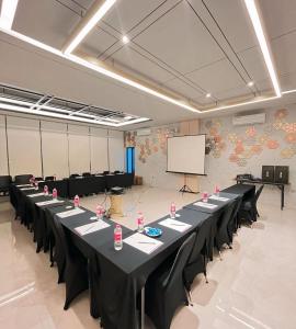 a conference room with tables and chairs and a screen at Laxston Hotel in Yogyakarta