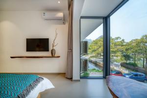 a bedroom with a bed and a large glass window at Guilin MeetSu Scenic Lake Boutique Hotel-Near Reed Flute Cave in Guilin