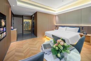 a hotel room with a bed and a table with flowers at Days Inn by Wyndham Kunming Wujiaba in Kunming