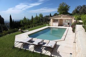 a swimming pool with two chairs and a house at Olives et Libellules in Vence