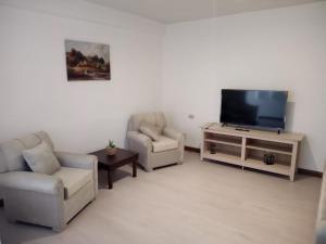 a living room with two chairs and a flat screen tv at San Roque Dpto in Cuenca