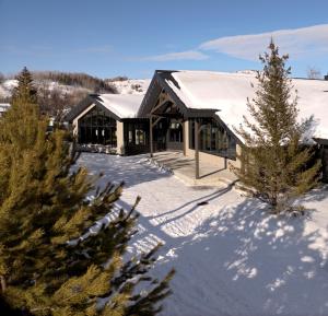 a house covered in snow with trees in the foreground at Altai Mountains Resort in Ülbi