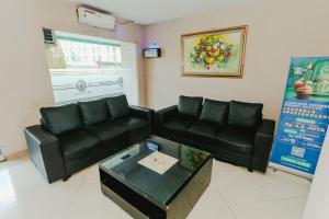 a living room with black leather couches and a table at Aurora Rooms Riverdale in Rawasuren