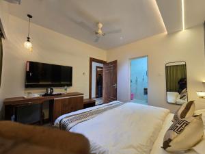 a bedroom with a bed and a desk and a television at Hotel Fortune in Ayodhya