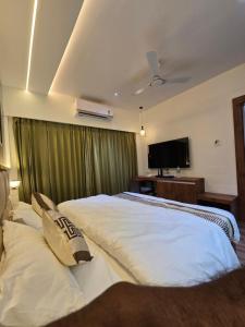 a bedroom with two beds and a flat screen tv at Hotel Fortune in Ayodhya