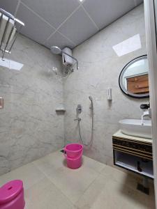 a bathroom with a shower and a sink and a bucket at Hotel Fortune in Ayodhya