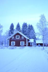 a wooden house in the snow with trees at Idyllic Peltola in Ranua