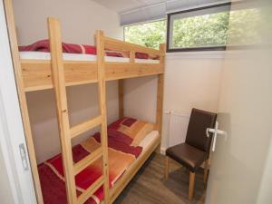 a bedroom with two bunk beds and a chair at Sint Maartenszee Renovated Family Retreat in Sint Maartenszee
