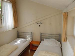 two beds in a small room with a window at Holiday home in Petten near beach in Petten