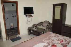 a bedroom with a bed and a couch and a television at Hotel Diamond Leaf in Chandīgarh