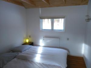 a white bedroom with a bed and a window at Holiday home Giethmen in Giethmen