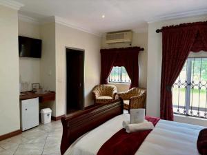 a bedroom with a bed and two chairs and a window at ARK Guesthouse in Potchefstroom +35 photos