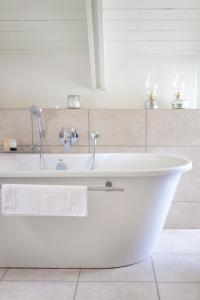 uma banheira branca com uma torneira na casa de banho em Klein Welmoed Luxury Guest House em Stellenbosch
