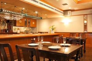 高知市にあるサウスブリーズホテル高知海月の木製のテーブルと椅子のあるレストラン、バー