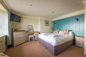 a bedroom with a large bed with a blue wall at The Edgcumbe Arms in Millbrook