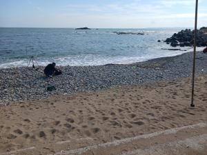 a person sitting on the beach near the water at Pohang Mimi House Pension in Pohang +15 photos